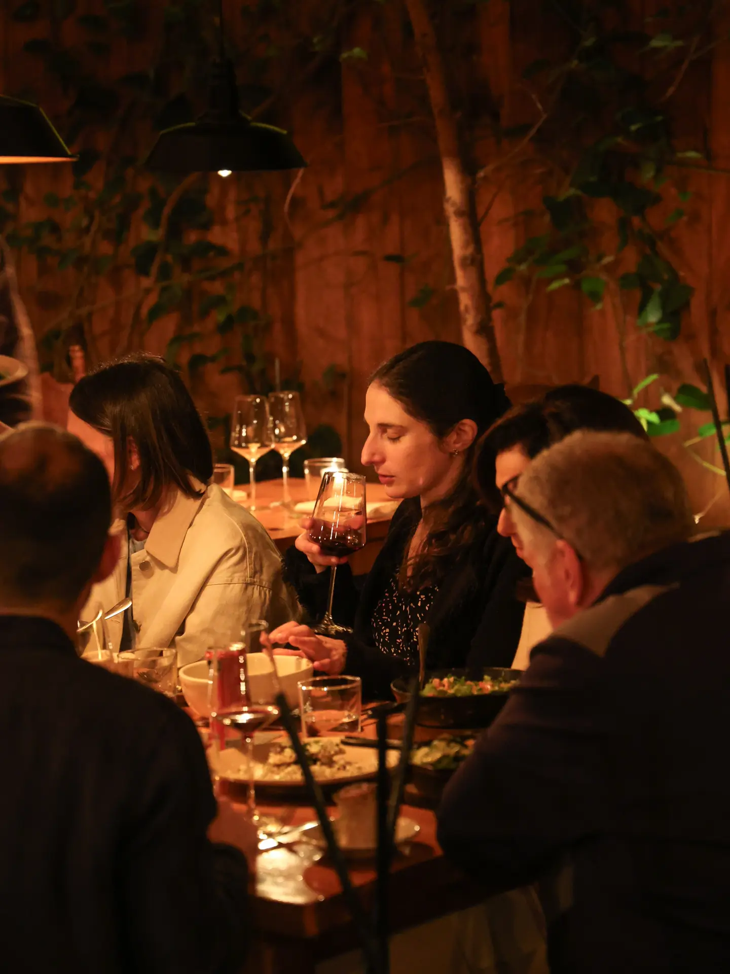 Comensales compartiendo la mesa bajo luz cálida y vegetación